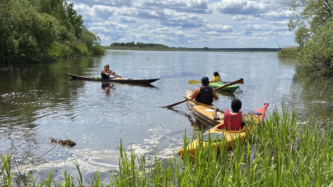 Besökare till evenemanget Friluftskul på Ekenabben 2023 fick prova på att paddla. Trekajaker är på väg ut på den spegelblanka Hammarsjön.