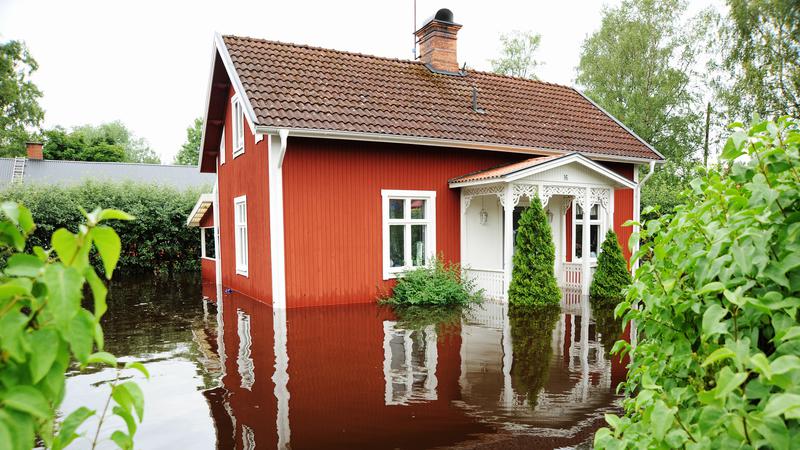 Översvämning vid ett rött hus. 